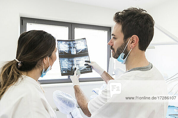 Male dentist showing x-ray to female assistant at medical clinic