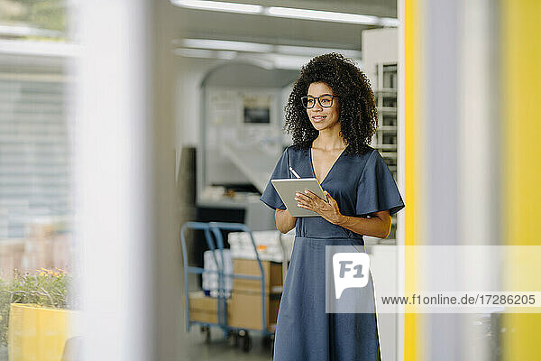 Female entrepreneur with digital tablet contemplating while standing in office