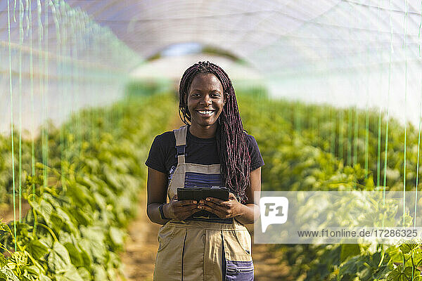 Smiling female farmer with braided hair at greenhouse