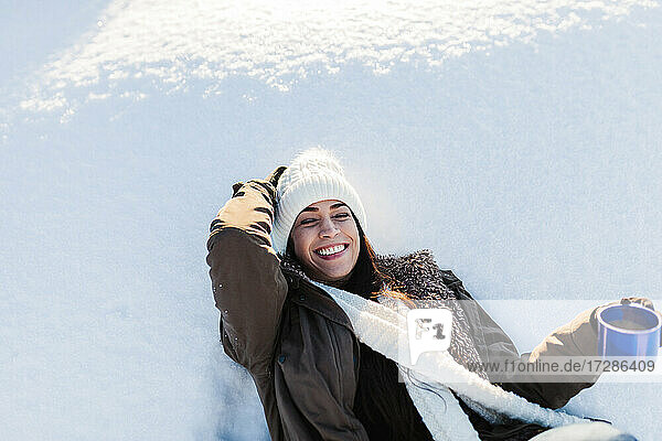 Fröhliche Frau genießt Kaffee im Schnee