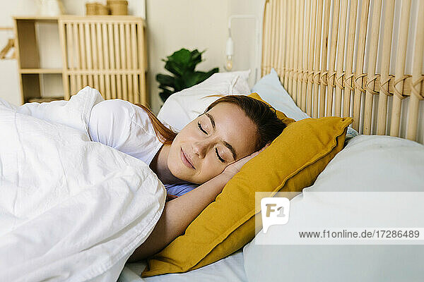 Beautiful woman with eyes closed asleep in bed at home