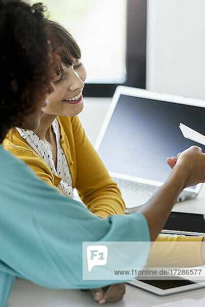 Smiling businesswomen discussing over business plan at desk in office