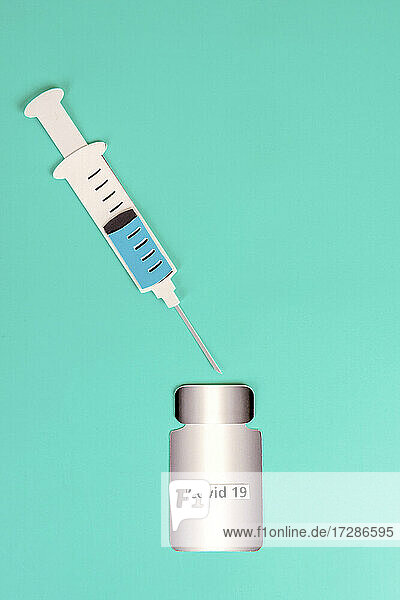 2D paper cutouts of filled syringe and bottle of vaccine