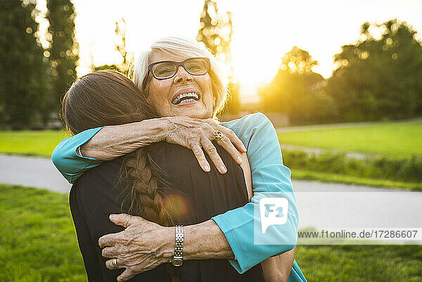 Großmutter umarmt ihre Enkelin im Park
