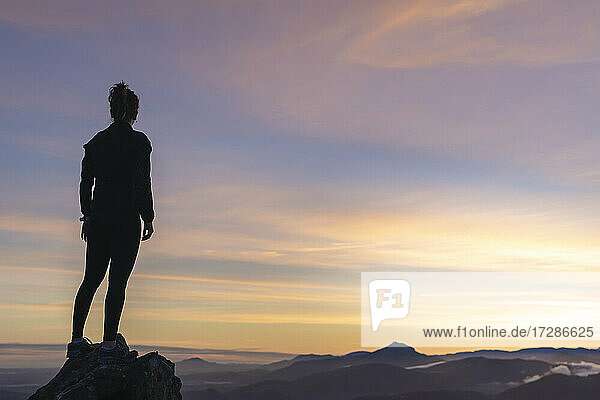Woman standing on rock while looking at sky