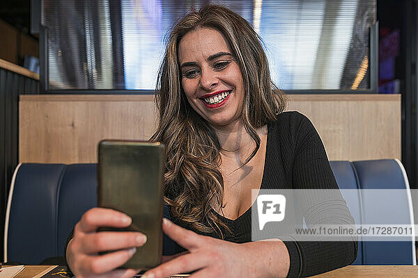 Lächelnde schöne Frau nimmt Selfie durch Smartphone im Restaurant