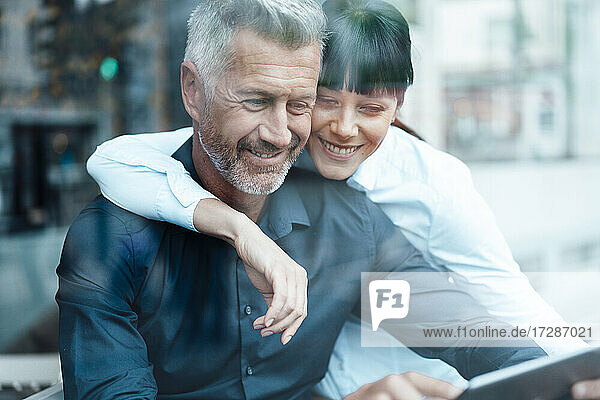 Geschäftspaar lächelt bei der Nutzung eines digitalen Tablets in einem Café
