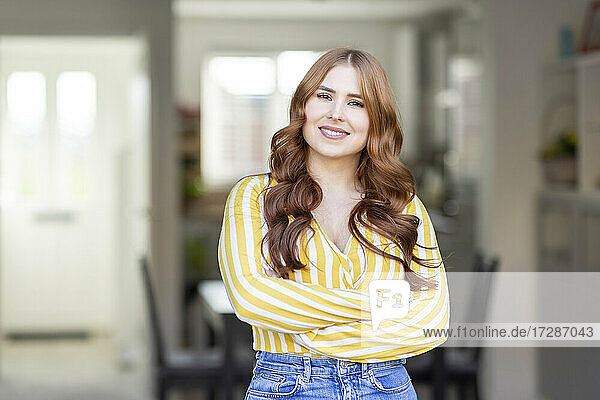 Smiling beautiful redhead woman standing with arms crossed
