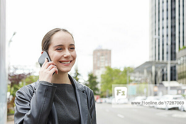 Geschäftsfrau lächelnd im Gespräch am Handy in der Stadt