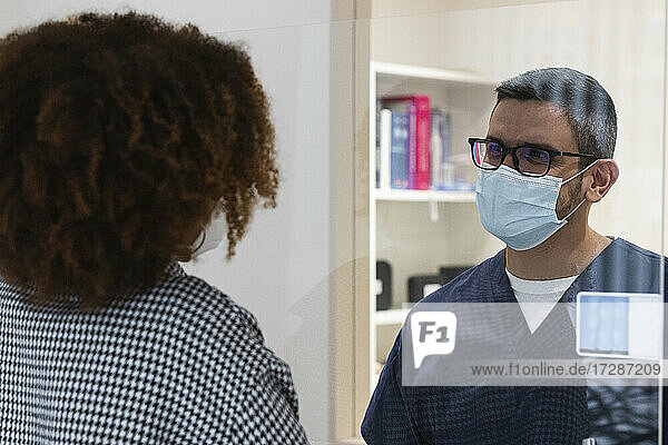Männlicher Zahnarzt im Gespräch mit einer Patientin in der Klinik