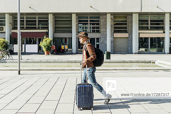 Mann mit Gepäck auf dem Fußweg an einem sonnigen Tag