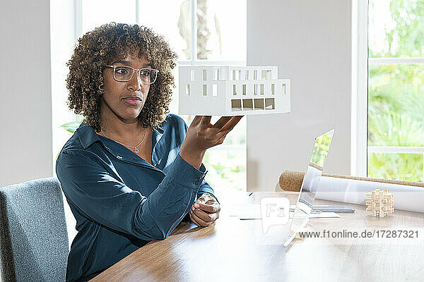 Geschäftsfrau  die ein Architekturmodell auf einem futuristischen Bildschirm am Schreibtisch überprüft