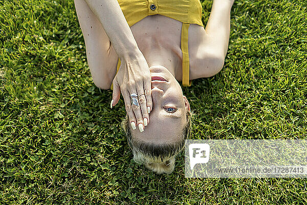 Frau bedeckt Auge  während sie im Gras liegt