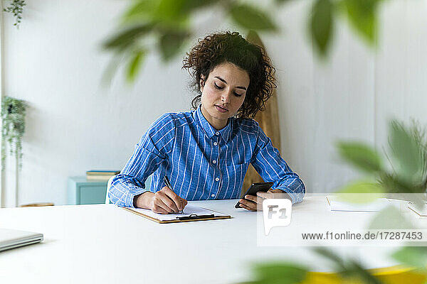 Businesswoman with mobile phone working in creative workplace, Businesswoman with mobile phone working in creative workplace