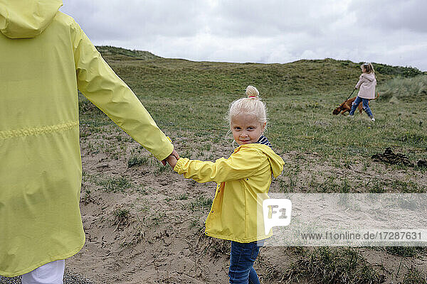 Niedliche Tochter hält die Hand der Mutter beim Spaziergang auf einem Hügel