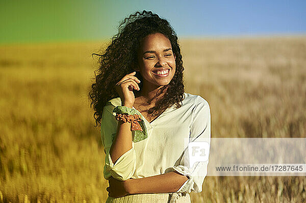 Glückliche junge Frau im Weizenfeld stehend