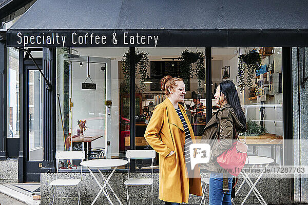 Smiling women talking outside coffee shop