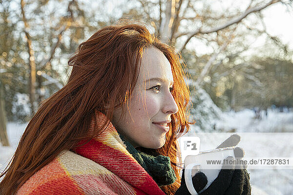 Rothaarige Frau schaut beim Kaffeetrinken im Winter weg