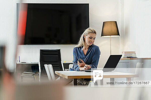 Unternehmerin mit Laptop am Schreibtisch sitzend im Büro