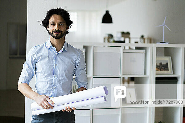 Junger männlicher Unternehmer  der ein Dokument hält  während er im Büro steht