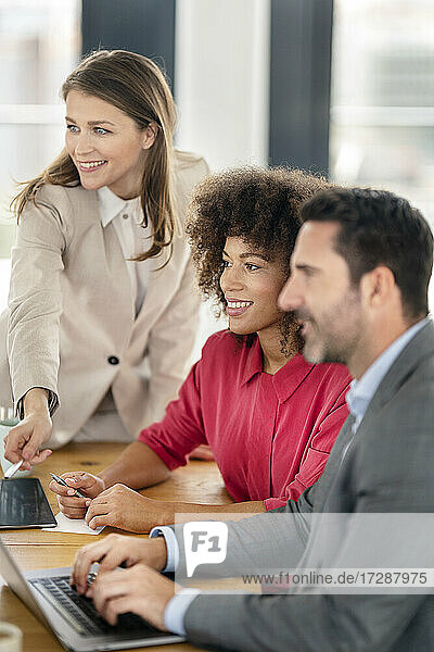 Smiling male and female entrepreneurs looking away at office