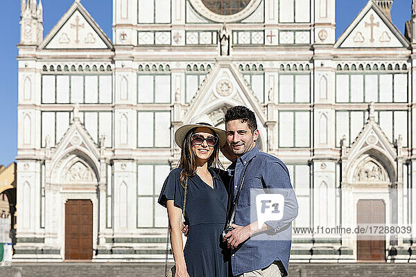 Smiling tourist couple standing in front of Basilica Of Santa Croce  Florence  Italy