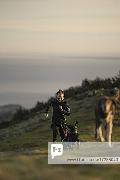 Junge Frau läuft mit Hunden im Canicross-Stil