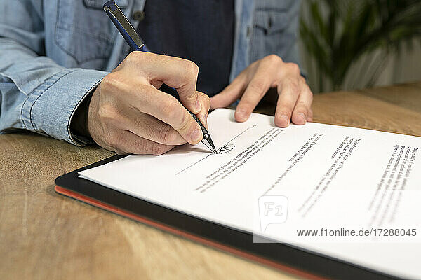 Businessman doing signature on contract at desk in office