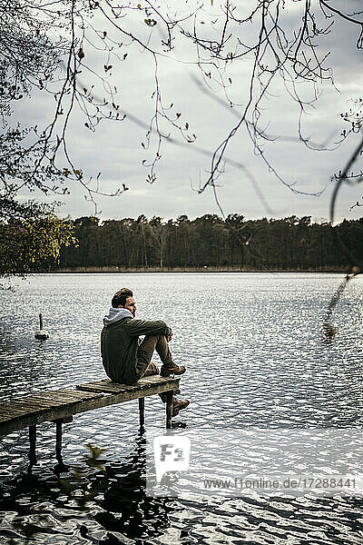 Man looking away while sitting on jetty over Seddinsee