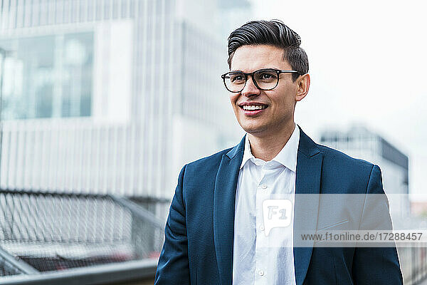 Lächelnder männlicher Berufstätiger mit Brille  der wegschaut