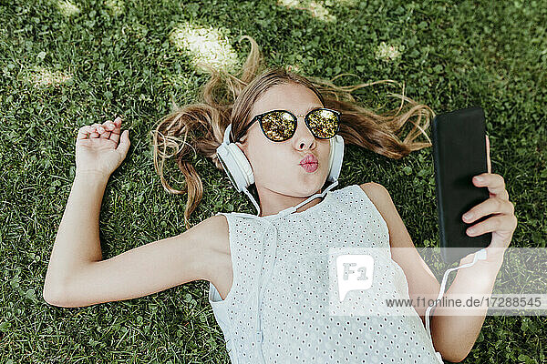 Girl puckering while lying on grass in summer