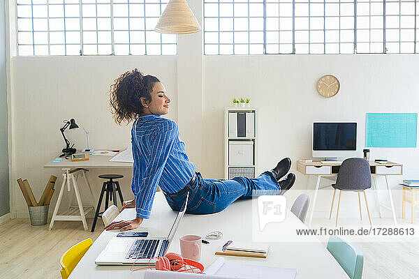 Female entrepreneur sitting by laptop on desk in office