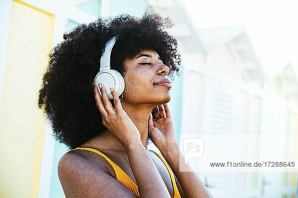Relaxed Afro woman listening music through headphones