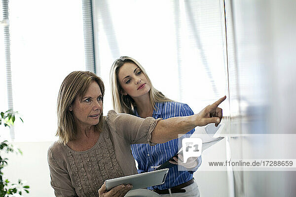 Businesswoman explaining charts to female colleague in office