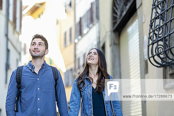 Lächelndes Paar  das wegschaut  während es auf der Straße steht