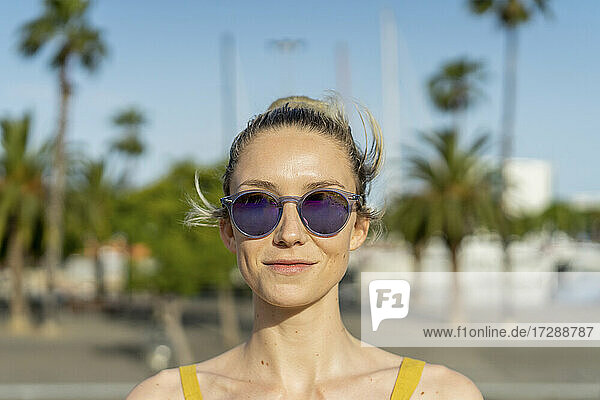 Lächelnde Frau mit Sonnenbrille an einem sonnigen Tag