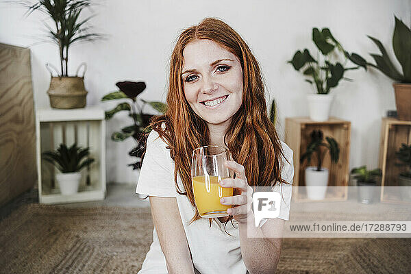 Smiling beautiful woman holding glass of juice at home