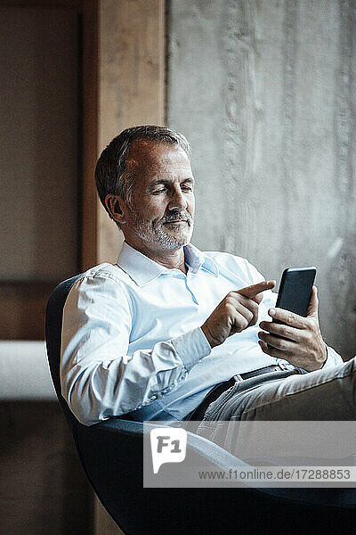 Male professional using smart phone while sitting on chair