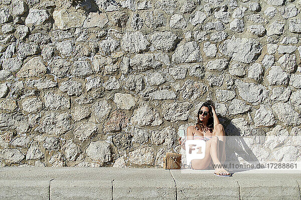 Frau  die ein Selfie macht  während sie vor einer Steinmauer sitzt