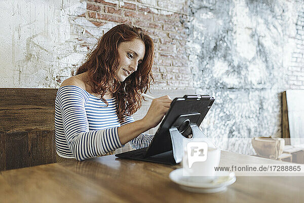 Weibliche Grafikdesignerin benutzt ein Tablet  während sie im Café sitzt