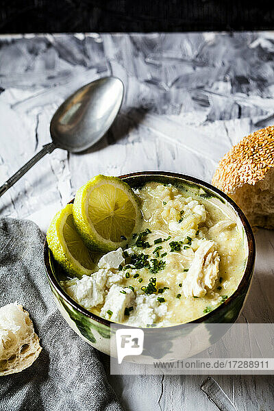 Schüssel mit griechischer Avgolemono-Suppe mit Reis  Zitronenscheiben und Brot