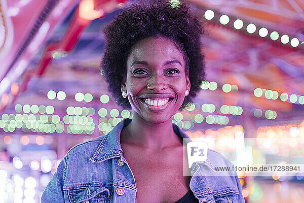 Lächelnde Frau im beleuchteten Vergnügungspark