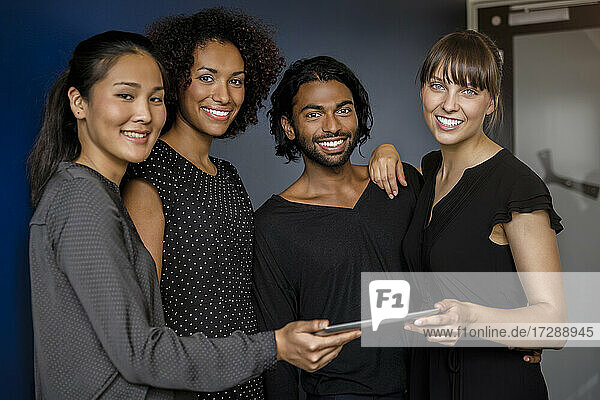 Lächelnde männliche und weibliche Fachkräfte mit digitalem Tablet während einer Besprechung im Büro