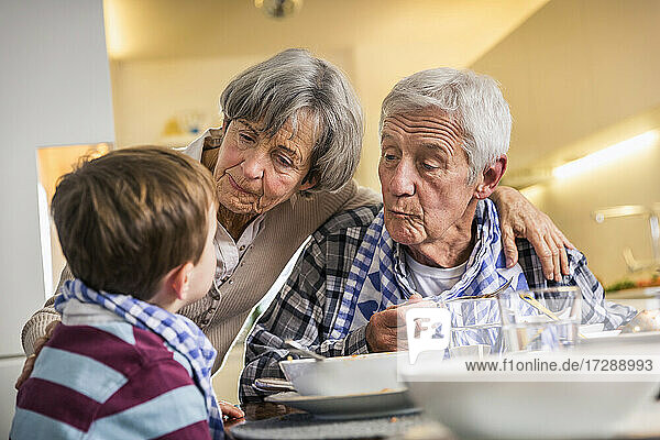 Grandparent looking at grandson while having food at home