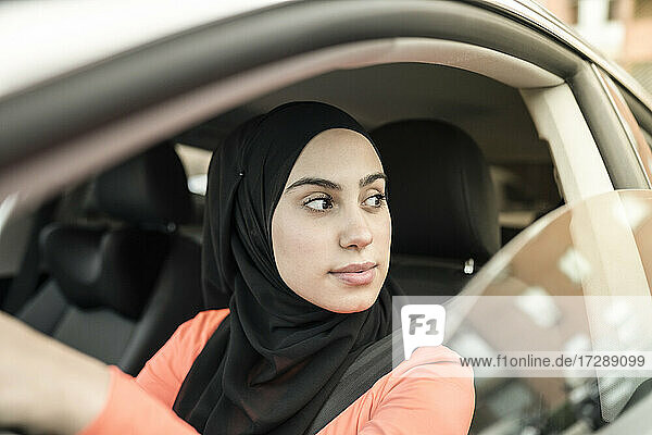 Arabische Frau schaut weg  während sie im Auto sitzt