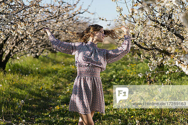 Schöne Frau kontempliert unter Kirschbäumen an einem sonnigen Tag