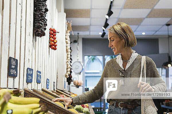 Woman checking fruit kept in retail display at supermarket