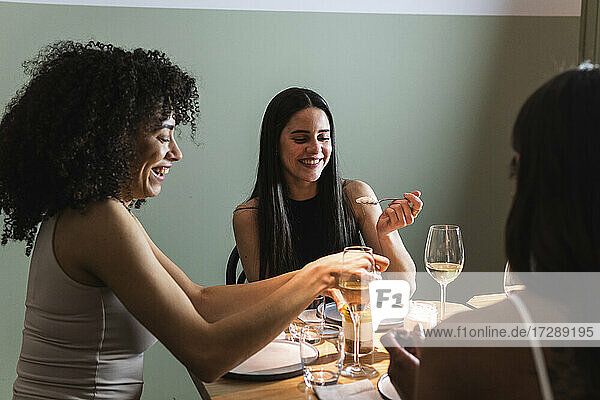 Smiling friends having food and drink together in restaurant