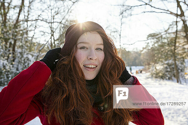 Lächelnde Frau mit Händen im Haar im Winter