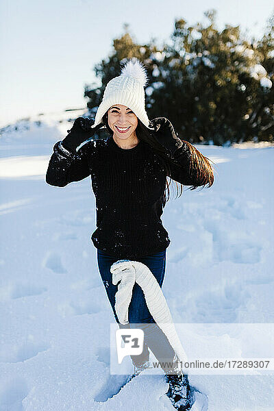 Smiling woman wearing knit hat enjoying in snow
